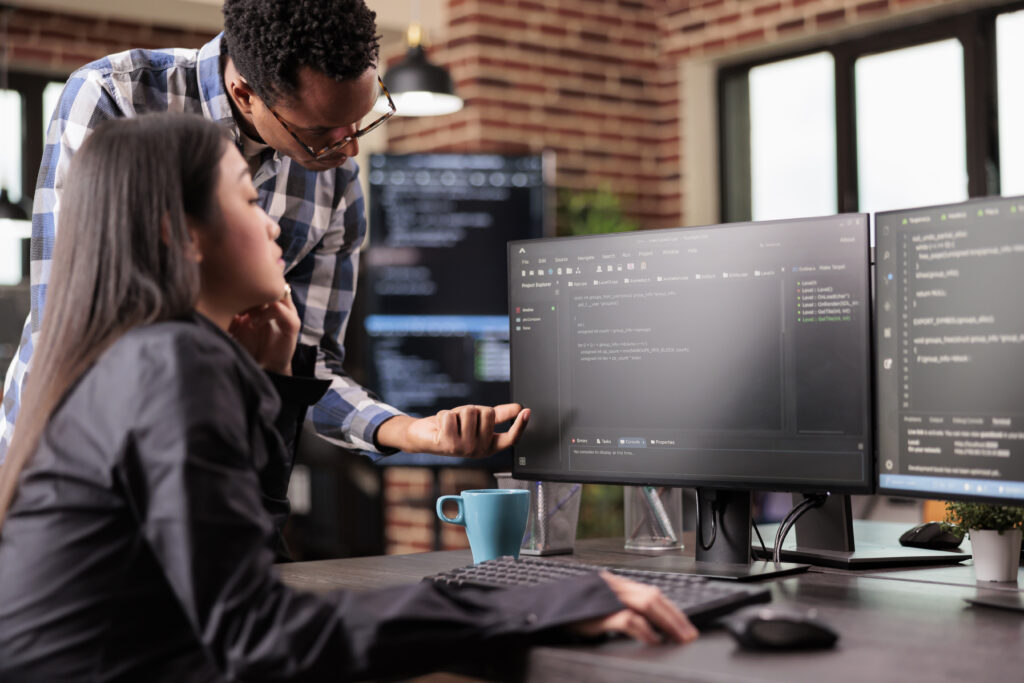 Diverse Programmers Discussing About Html Code Compiling Discovers Errors Standing Front Multiple Screens Startup Office Software Developers Working Server Interface Development 1024x683